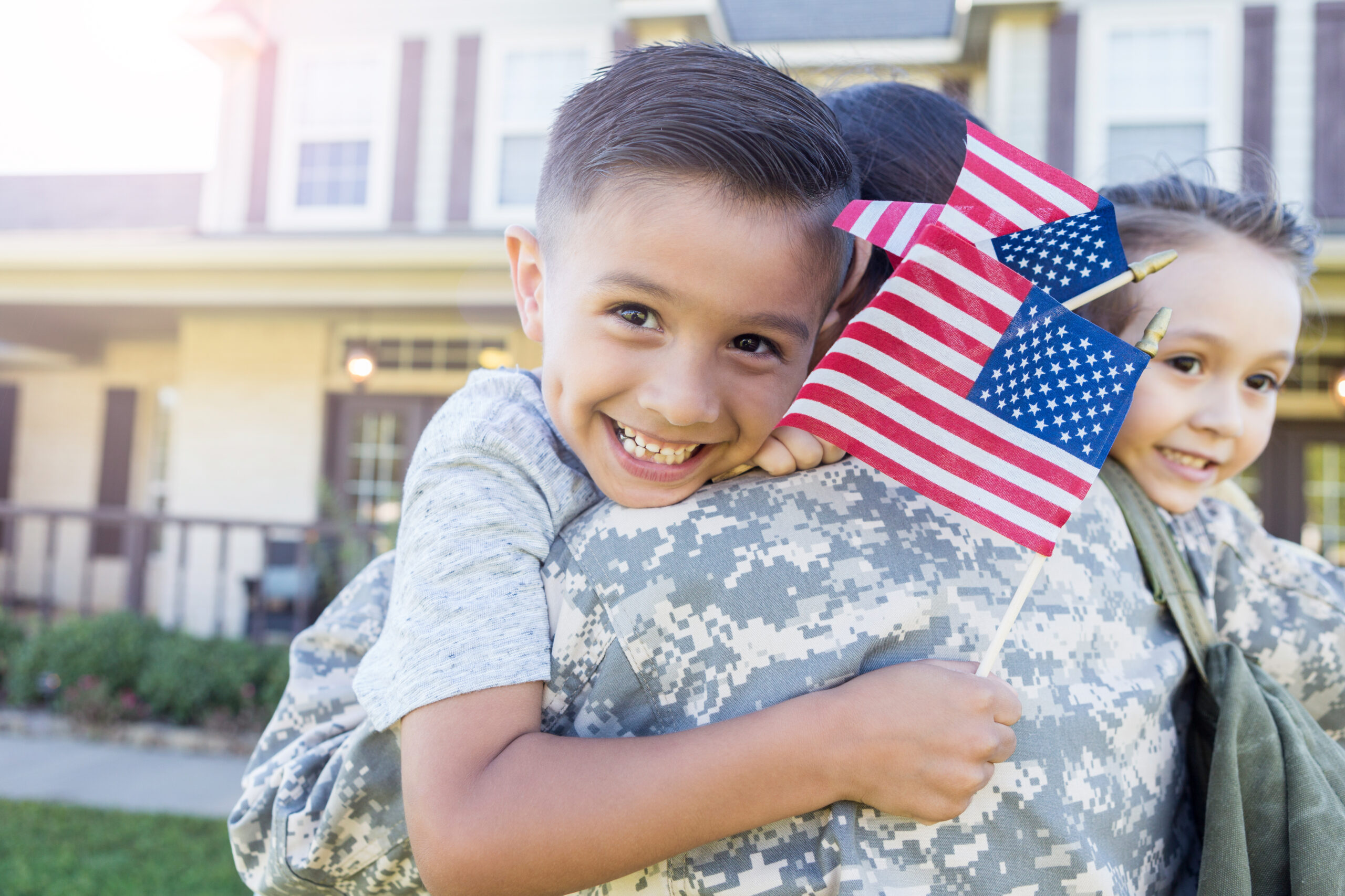 Military Family. Child hugging military parent while holding a flag